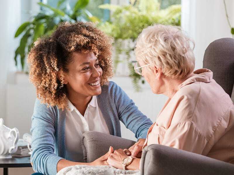 Care associate and resident holding hands